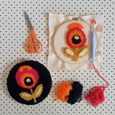 two crocheted flowers are sitting on a table next to some yarn and scissors