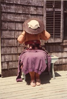 a woman in a hat sitting on a bench with her back turned to the camera