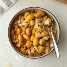 a bowl filled with food sitting on top of a white counter next to a spoon