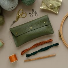 the contents of a purse laid out on a table next to yarn, scissors and knitting needles