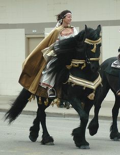 two people riding on the back of black horses