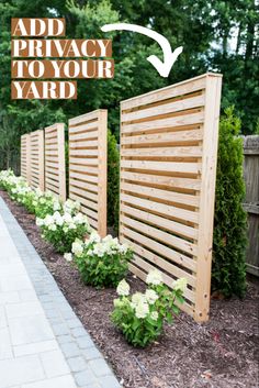 a wooden privacy fence with white flowers in the foreground and an arrow pointing to it