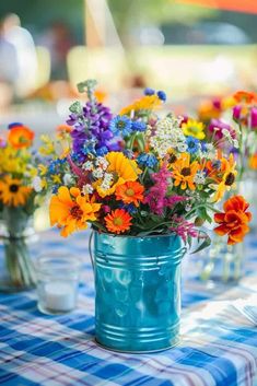 colorful wildflowers are in a blue bucket on a checkered cloth tablecloth