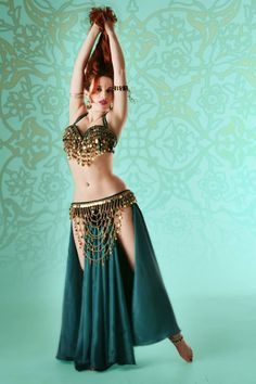 a woman in a belly dance outfit with chains on her waist and hands behind her head