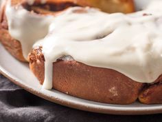 a white plate topped with cinnamon rolls covered in icing