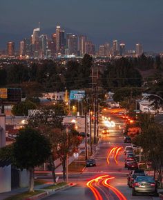 the city skyline is lit up at night, with cars driving down the street in front of them