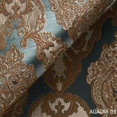 a blue and gold brocaded fabric with an intricate design on it's side