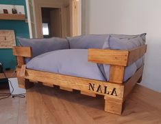 a couch made out of pallets with pillows on it and the word nala written in black