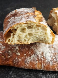 a loaf of bread is cut in half and sitting on a black surface with one piece missing