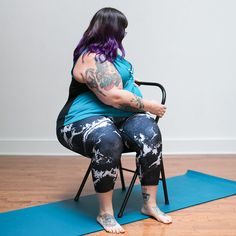 a woman sitting in a chair on top of a blue mat with her legs crossed