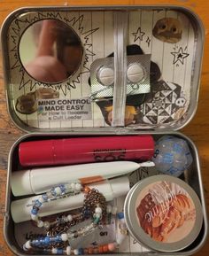 an open metal container filled with assorted items on top of a wooden table next to a mirror