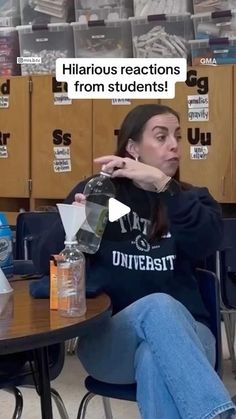 a woman sitting at a table with a bottle in her hand