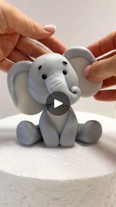 someone is decorating a cake with an elephant figurine