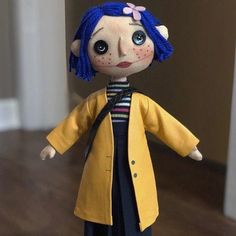 a doll with blue hair wearing a yellow coat