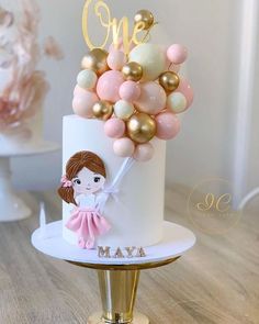 a white cake with gold and pink balloons on top