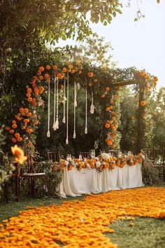 A vibrant fall garden wedding setup featuring an arch adorned with orange flowers and greenery, and a petal-covered aisle with warm autumn colors. Garden Setup, Garden Wedding Decor, Garden Wedding Decorations