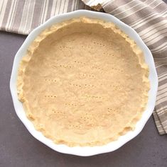 an uncooked pie crust in a white bowl on top of a striped napkin