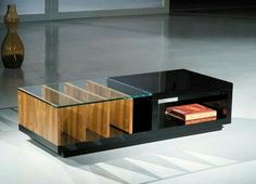 a coffee table with a glass top and wooden cabinet in the middle, next to a vase