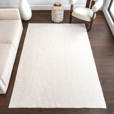 a living room with a white rug and two chairs in front of the couches