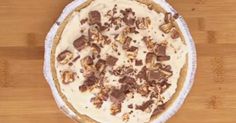 a pie sitting on top of a wooden table covered in nuts and chocolate toppings