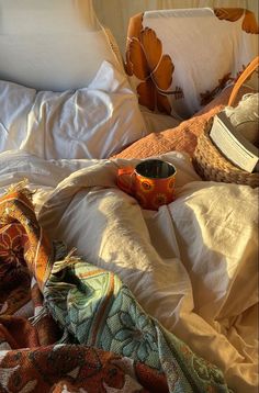 an unmade bed with white sheets and blankets on top of it, including a book