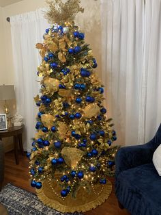 a blue and gold christmas tree in a living room