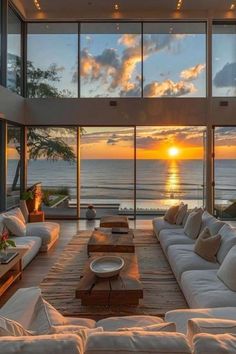 the living room is filled with white couches and large windows that overlook the ocean