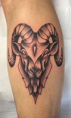 a black and white photo of a ram's head tattoo on the calf leg