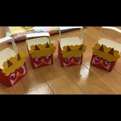 four little boxes with crowns on them sitting on the floor in front of a table