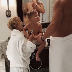 a man in a bathrobe is brushing his teeth while two other men stand nearby