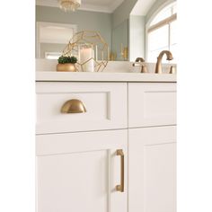 a bathroom with white cabinets and gold knobs on the door handles is seen in this image