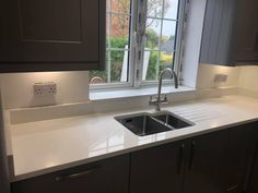 a kitchen sink sitting under a window next to a counter top with a faucet