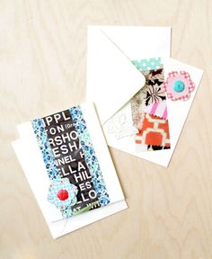 two greeting cards on a table next to an envelope with some paper and buttons in it