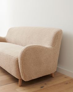 a couch sitting on top of a hard wood floor next to a white painted wall