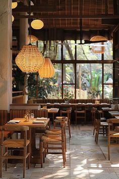 a restaurant with wooden tables and chairs in front of large windows that look out onto the jungle