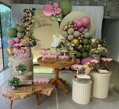 a table with cakes and flowers on it in front of a birthday cake display at a party