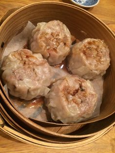 some dumplings are in a wooden bowl on a table next to chopsticks