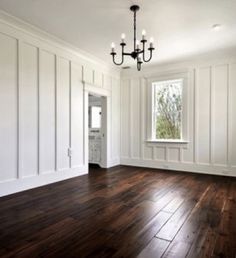 an empty room with hard wood flooring and white paneling on the walls is shown