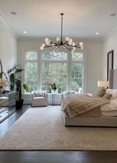 a bedroom with a large bed and lots of windows in the room, along with a chandelier hanging from the ceiling