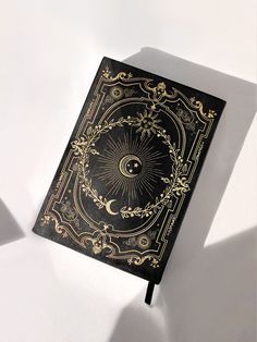 a black and gold book sitting on top of a white table