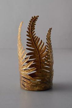 a gold fern leaf crown on a table with grey background and copy space in the bottom right corner