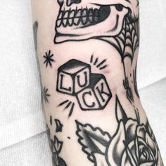 a person with a tattoo on their arm has a skull and dice in front of them