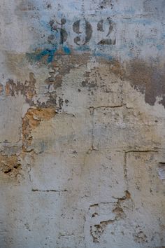 an old wall with peeling paint and numbers painted on it