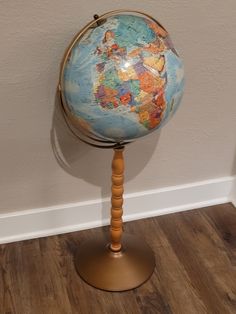 a small wooden stand with a globe on it's top, and a white wall in the background