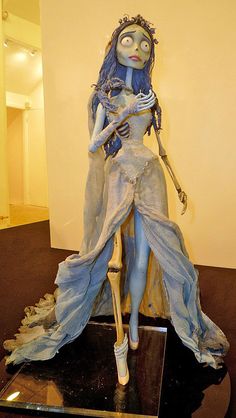 a statue of a woman with blue hair and makeup is on display in a museum