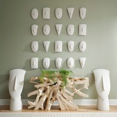 there is a table made out of driftwood and white vases on the wall