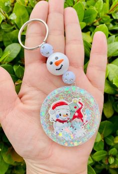 a hand holding a keychain with a snowman on it