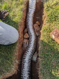 a man laying on the ground next to a large pipe with water coming from it