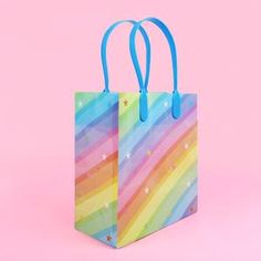 a colorful shopping bag with stars and rainbow stripes on it, against a pink background