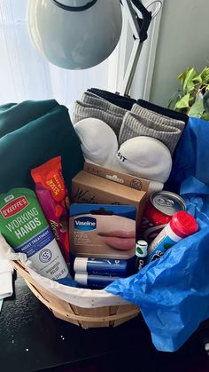 a basket filled with diapers and other items sitting on a table next to a lamp